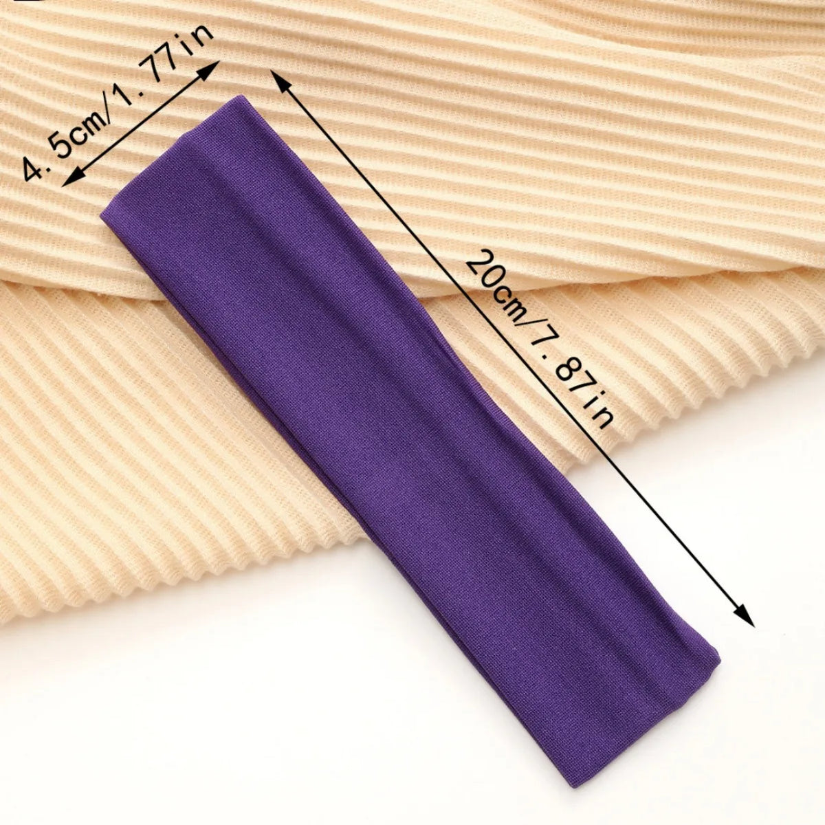 Purple stretchable cotton sweat absorbing headband shown next to a beige ribbed fabric.
