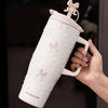 A hand holds a white insulated thermos mug decorated with pink pearl inlay patterns.