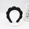 Black sponge terry cloth headband for hair styling displayed on a white circular stand.