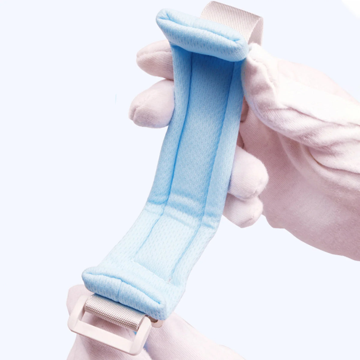 A hand is adjusting a light blue adjustable child safety harness and leash for toddlers.