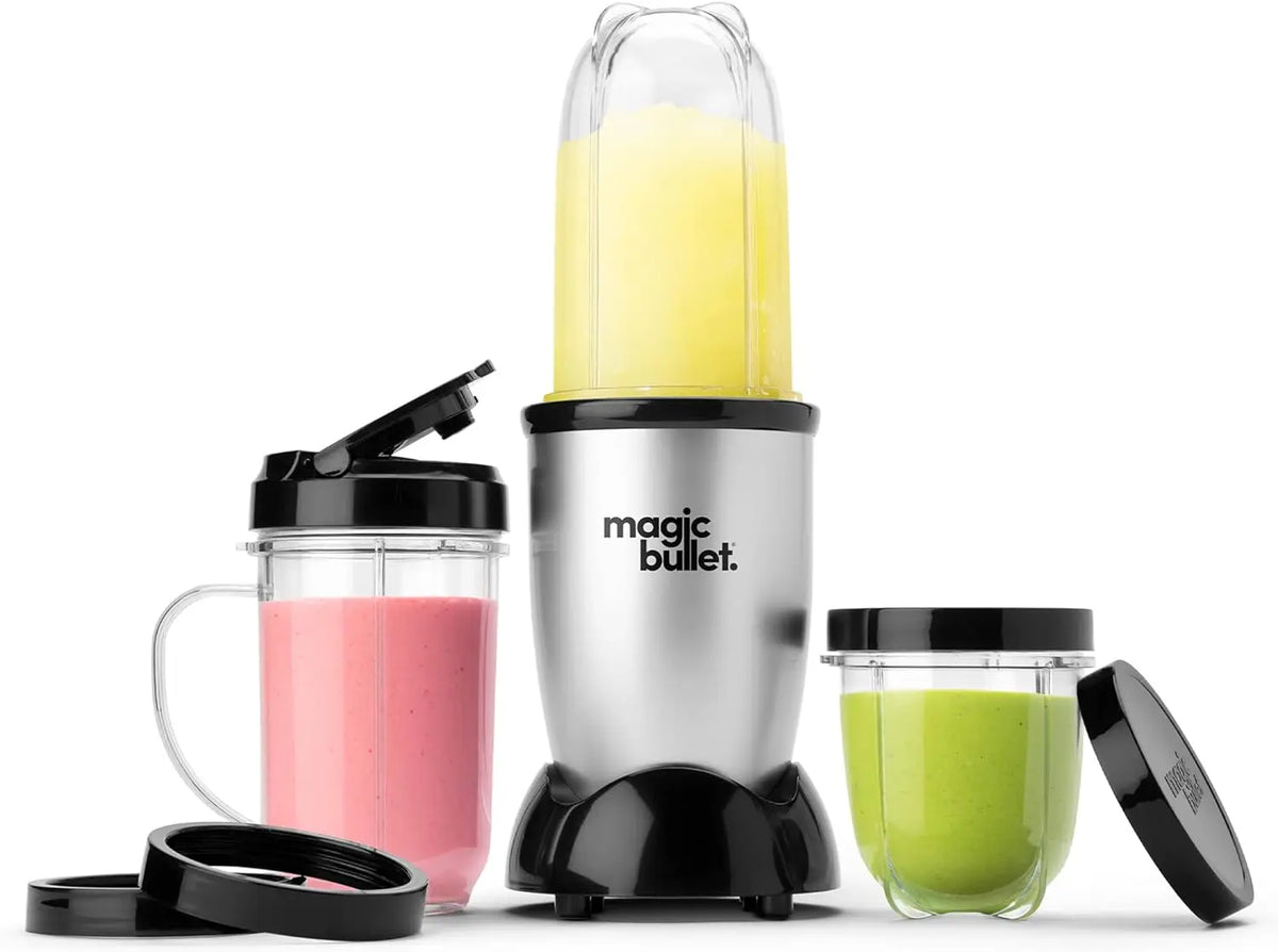 Set de licuadora Magic Bullet plateada y negra con líquido amarillo en el vaso principal y verde en un accesorio