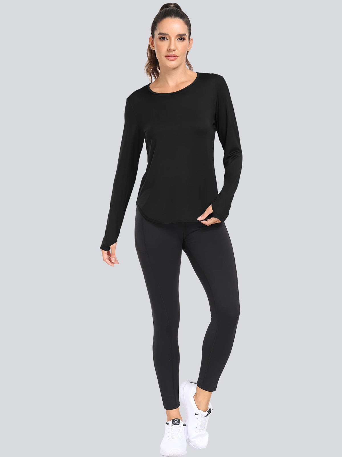 A woman models a black loose fit sun protection t-shirt and black leggings.
