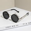 A pair of black round sunglasses with silver frames and adjustable dimming features resting on a white box.