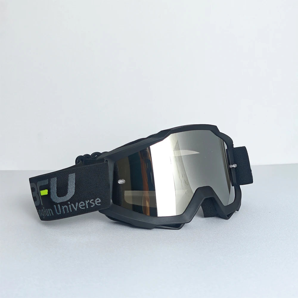 A pair of black sport-grade skiing goggles with reflective lenses and a black strap resting on a white surface.