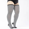 A pair of black and white striped thigh high leg warmers worn on a person's legs.