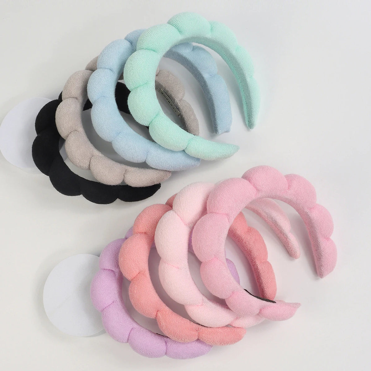 A set of pastel-colored microfiber skincare headbands and wristbands in shades of blue, green, pink, and gray.