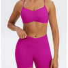A model wearing a bright magenta seamless high-waist yoga set consisting of a cropped top and matching shorts.
