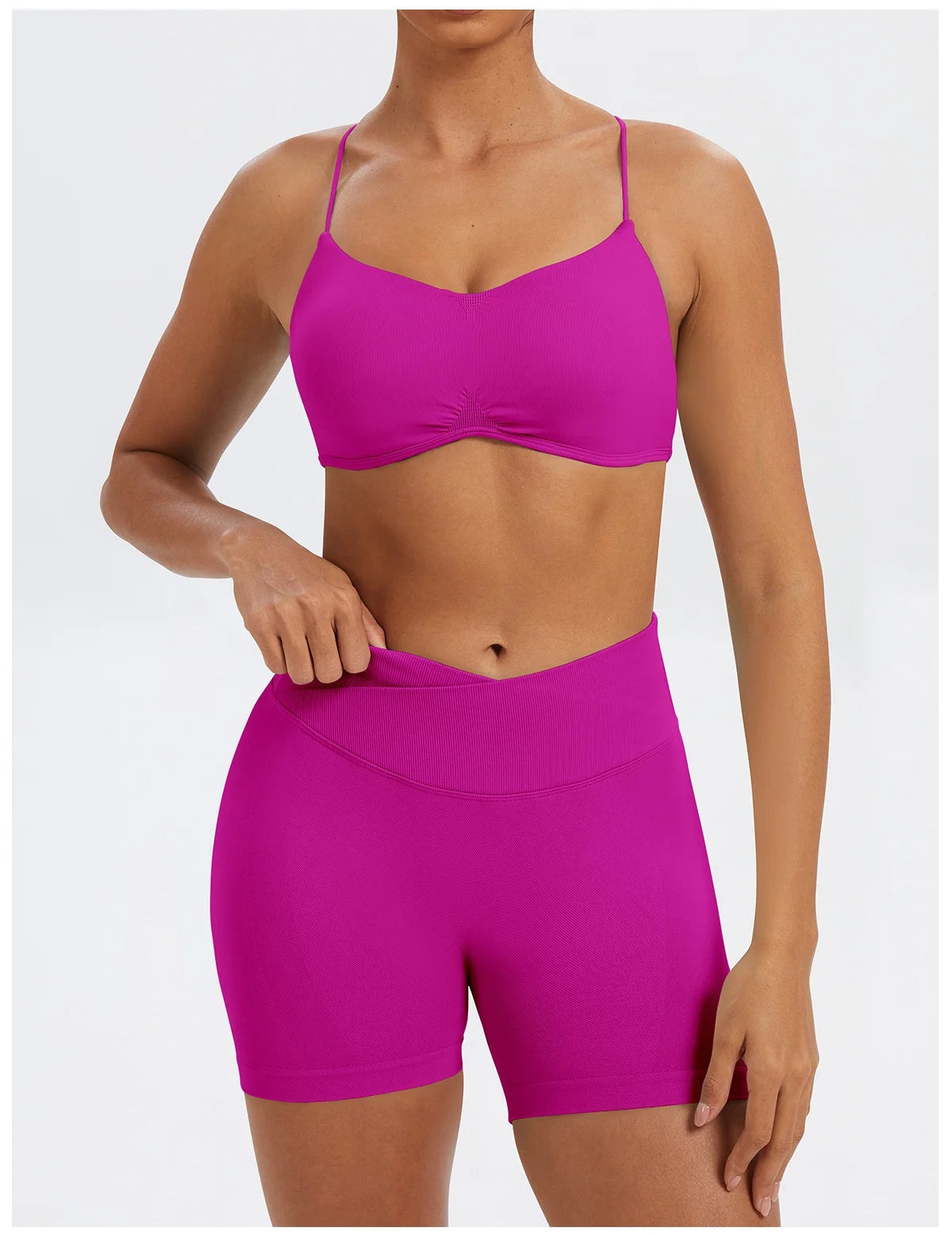 A model wearing a bright magenta seamless high-waist yoga set consisting of a cropped top and matching shorts.