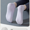 A pair of light purple yoga socks worn on a foot, displayed against a gray mat.