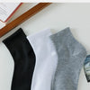 Ein Set aus drei weichen und bequemen Socken in Schwarz, Weiß und Grau auf einer hellen Oberfläche.