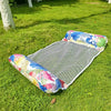 A colorful inflatable pool float hammock lying on green grass.