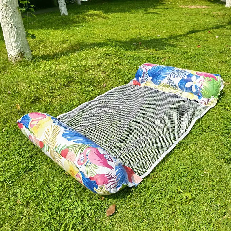 A colorful inflatable pool float hammock lying on green grass.