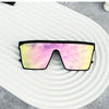 Retro square sunglasses with a vibrant pink and yellow gradient lens resting on a white, wavy surface.