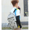 A person wearing a gray and blue backpack stands outdoors, looking to the side.