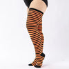 A pair of plus size striped thigh high leg warmers in black and orange are shown on a person's leg.