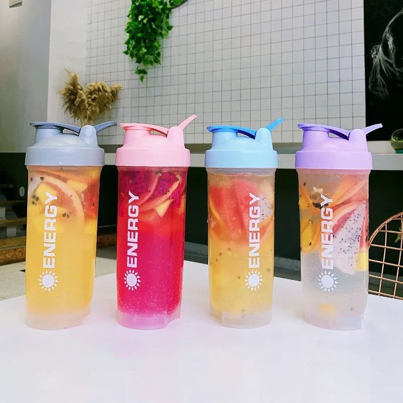 Vier bunte, tragbare Proteinpulver-Shakerflaschen auf einem weißen Tisch