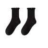 A pair of black cotton ruffle ankle socks shown against a white background.