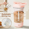 A pink automatic stirring cup is shown with a hand holding it, demonstrating its use for mixing beverages.