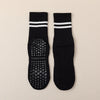 Pair of black grip socks with white stripes and studded soles for yoga and barre