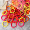 A pile of 50 mixed color elastic hair bands in bright orange, yellow, and pink.