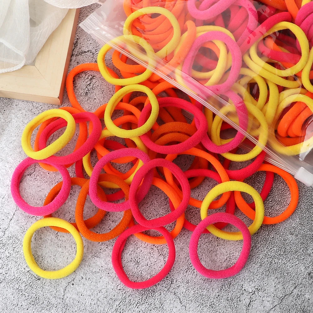 A pile of 50 mixed color elastic hair bands in bright orange, yellow, and pink.