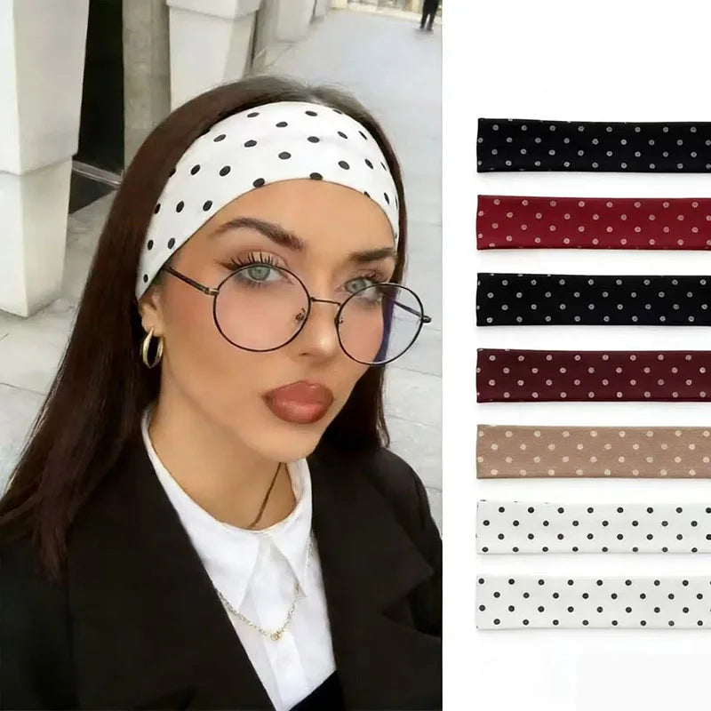 امرأة تعرض بليزر أسود وقميص أبيض وربطة رأس مطاطية منقطة لليوغا واللياقة البدنية.