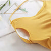 A yellow women's cross strap sports bra is shown on a white surface.
