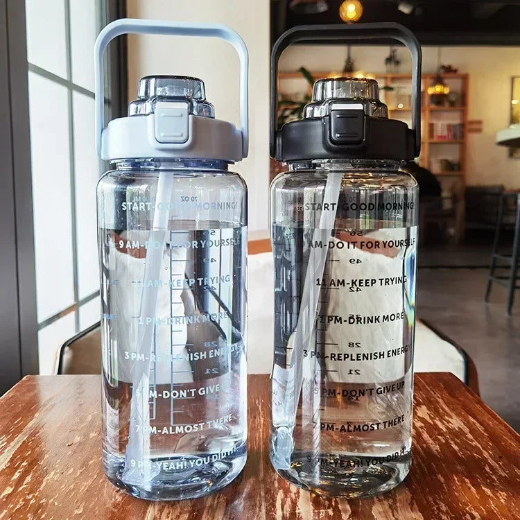 A clear insulated water bottle with a silver cap and straw is shown on a wooden table.