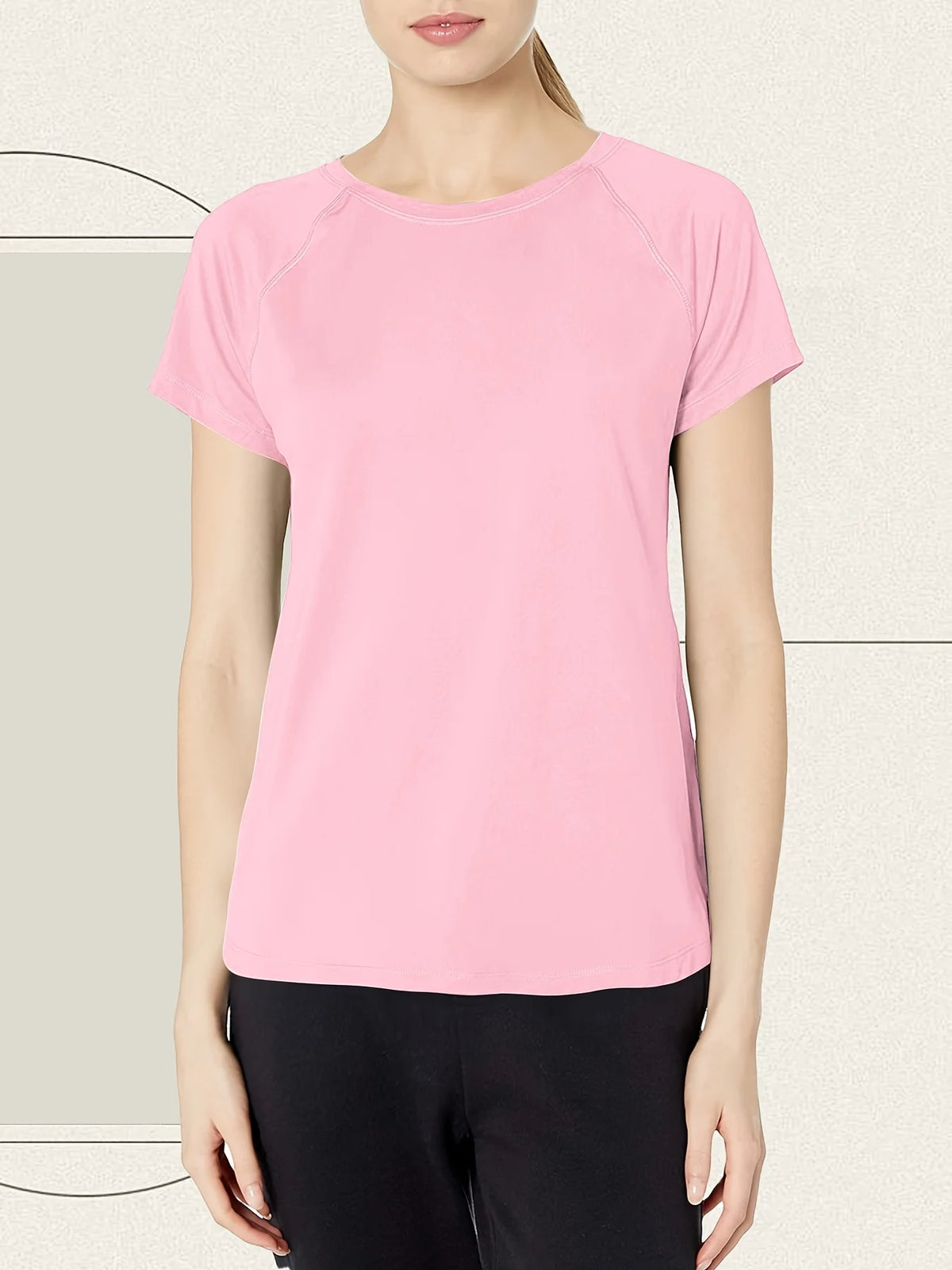 A woman wearing a pink women's quick dry moisture-wicking gym t-shirt and black pants.