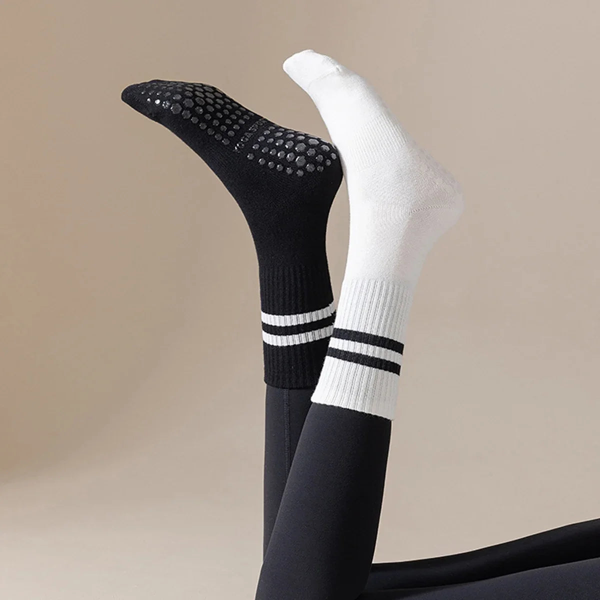 A pair of black and white Pilates grip socks shown vertically.