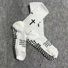 A pair of white athletic socks with black cross patterns and text printed on the foot.