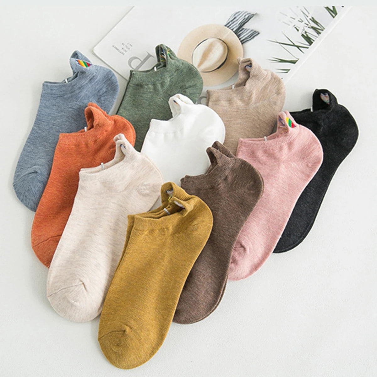 A collection of ten embroidered ankle socks in various muted colors and textures laid out on a white surface.