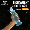 A hand holds a lightweight, foldable silicone water flask with a blue tint against a dark, leafy background.