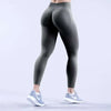 Eine Person trägt dunkelgraue, hochgeschnittene, nahtlose Yoga-Leggings und weiße Sportschuhe.