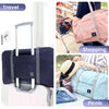 A foldable travel duffel bag in navy blue and light pink is shown with a rolling suitcase and a light blue bag being used for