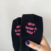 Black knitted socks with pink embroidery that reads What is forsnick toda