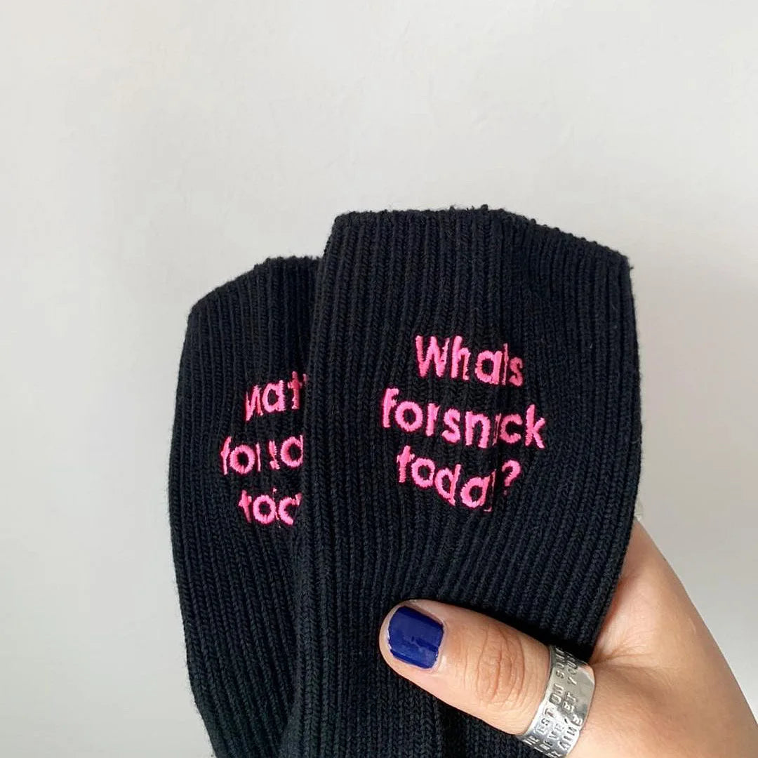 Black knitted socks with pink embroidery that reads What is forsnick toda