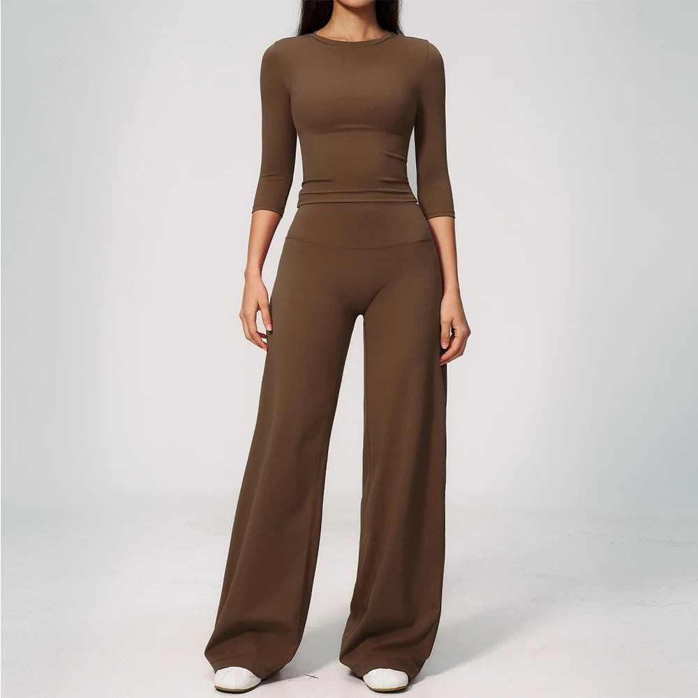 A woman wearing a matching brown long-sleeved top and high-waisted leggings set for yoga or fitness.