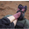 Purple and pink breathable performance running socks are shown on a person's foot, resting near a green bag.