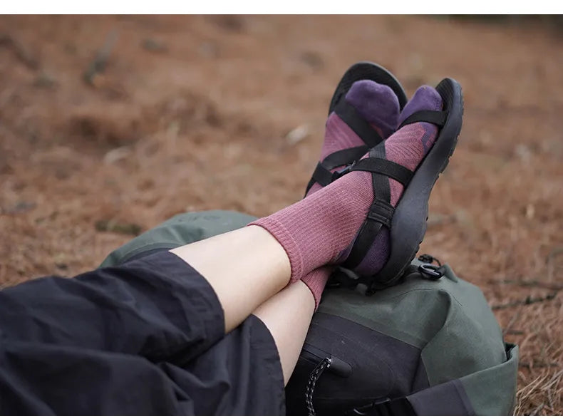 Purple and pink breathable performance running socks are shown on a person's foot, resting near a green bag.