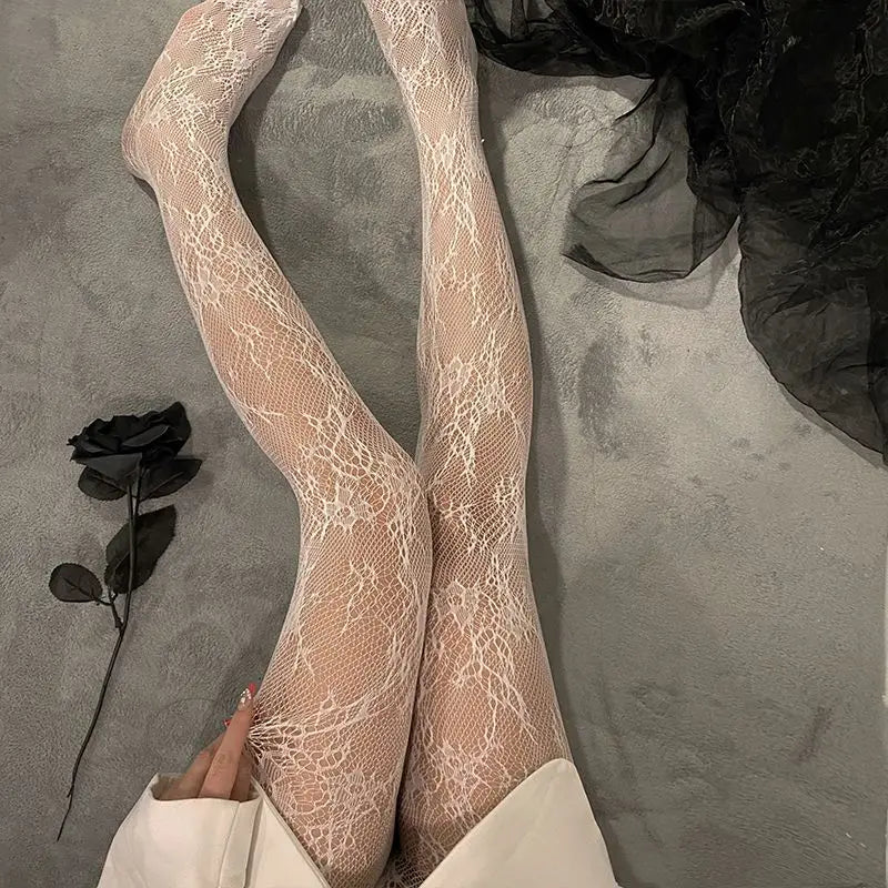 Pair of sheer beige floral rattan fishnet hosiery worn on legs against a gray background.