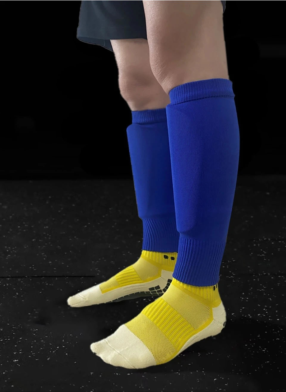 A close-up of a person's lower leg wearing royal blue compression socks and yellow athletic shoes.