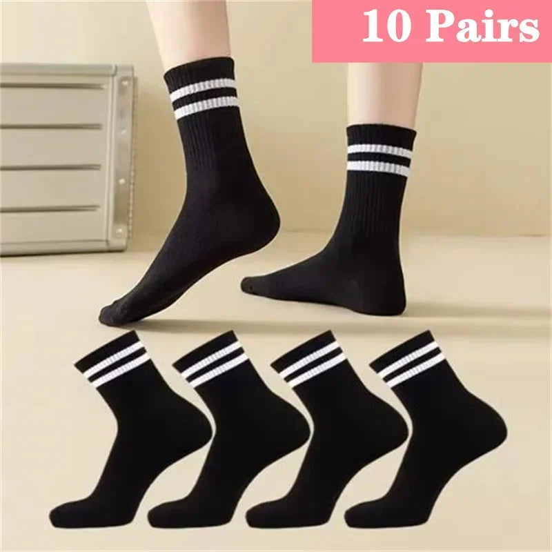 Ten pairs of black socks with white stripes displayed on a person's leg.