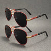 A pair of black sunglasses with red accents and gold detailing resting on a gray surface.
