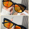 Black and yellow vintage square cat eye sunglasses with orange lenses shown on a hand