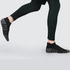 A person wearing black athletic leggings and dark socks is shown in a side view.