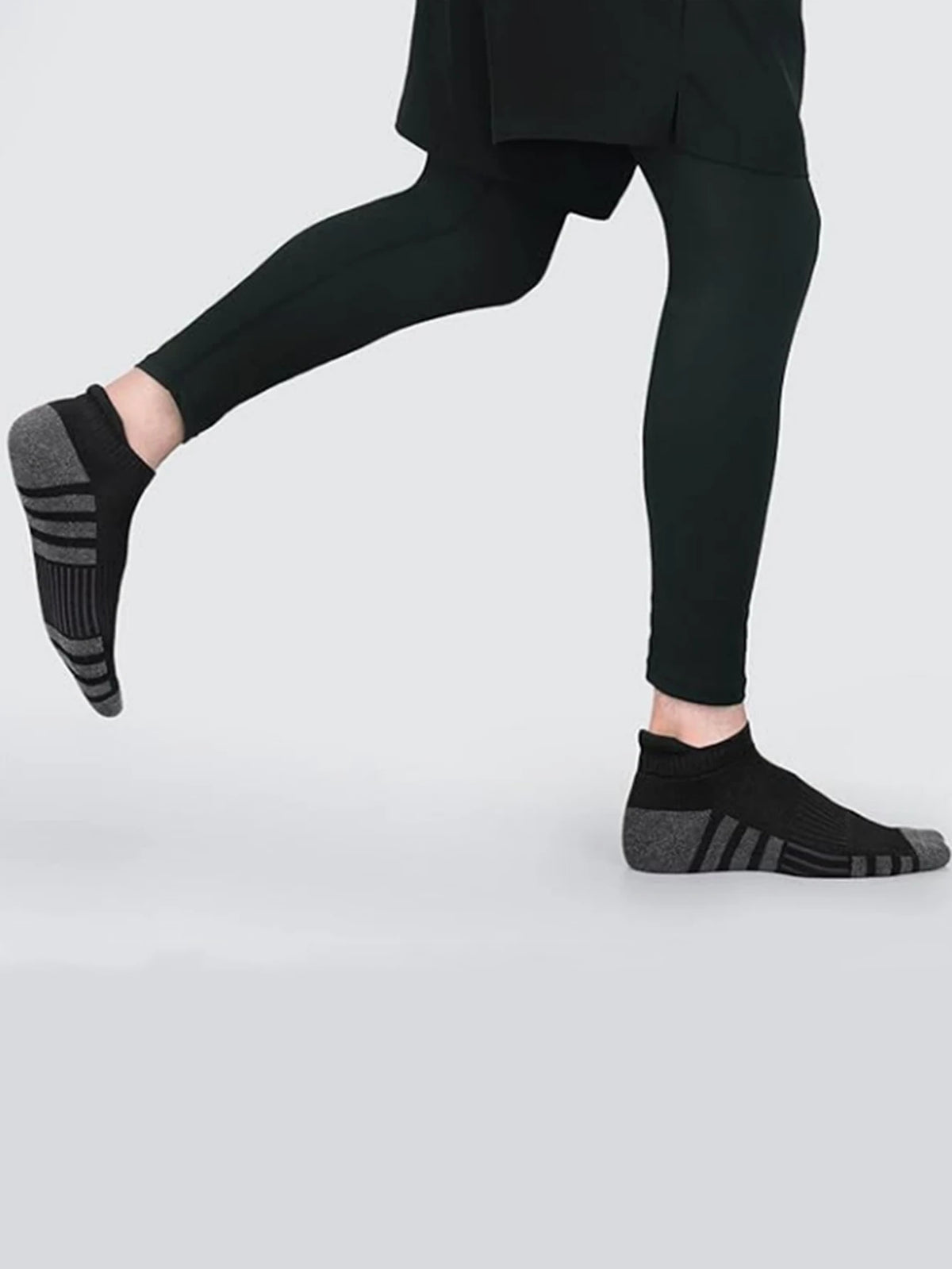 A person wearing black athletic leggings and dark socks is shown in a side view.