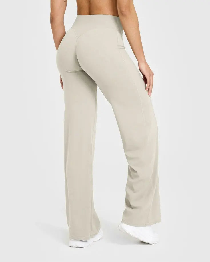 A model is wearing beige high-waist yoga pants in a full-length shot.