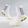 Un par de calcetines deportivos blancos de fútbol con detalles amarillos y puntos negros, vistos de lado.