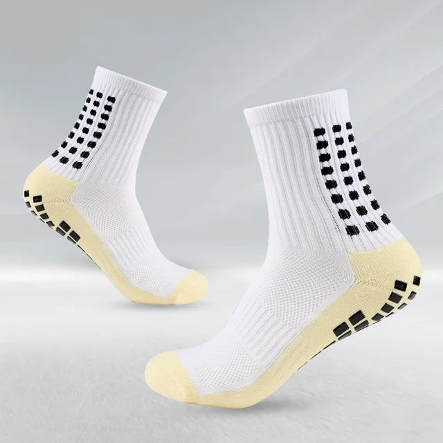 Un par de calcetines deportivos blancos de fútbol con detalles amarillos y puntos negros, vistos de lado.